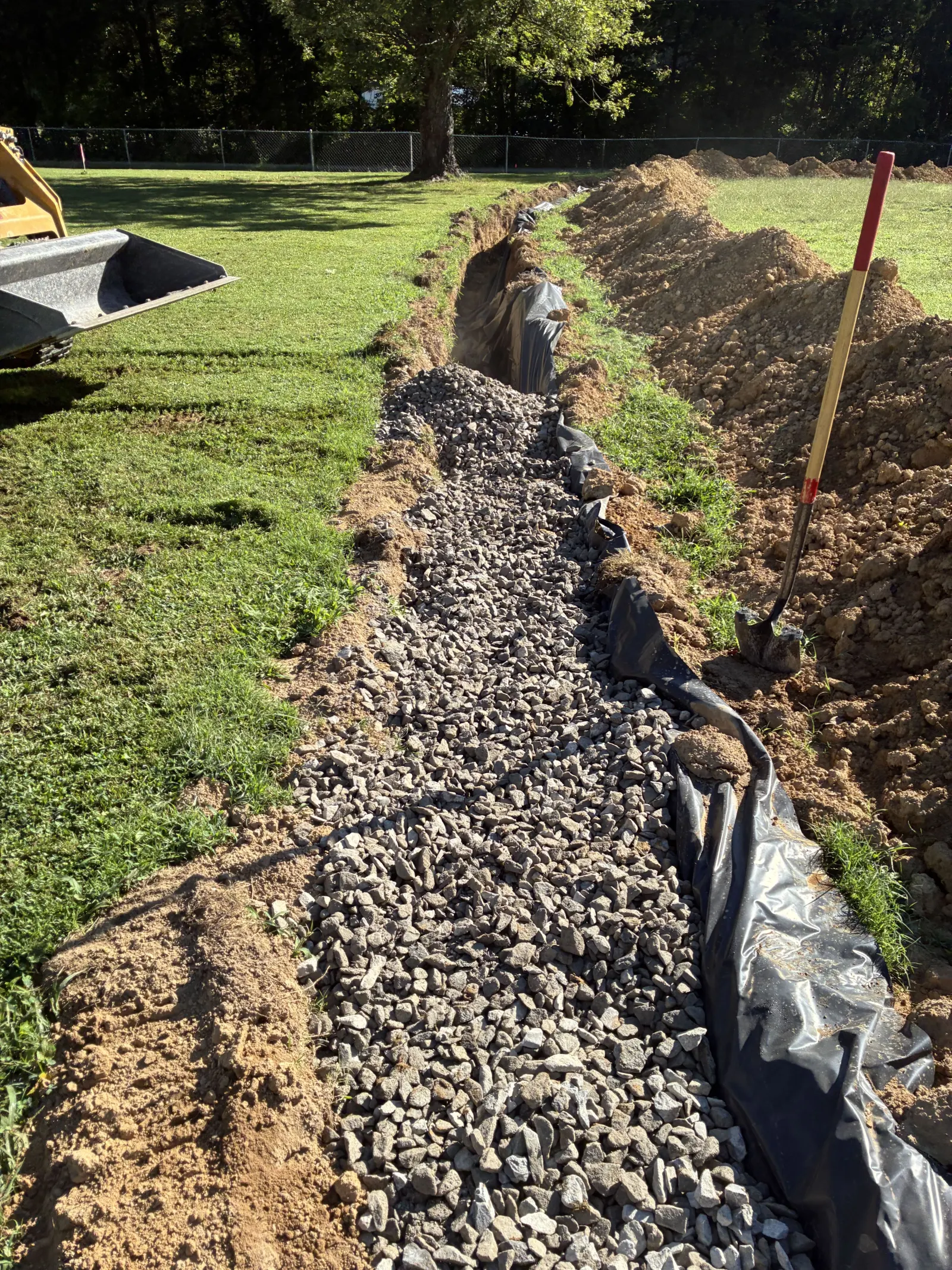 Gravel filled drain field trench lined with fabric across a lawn
