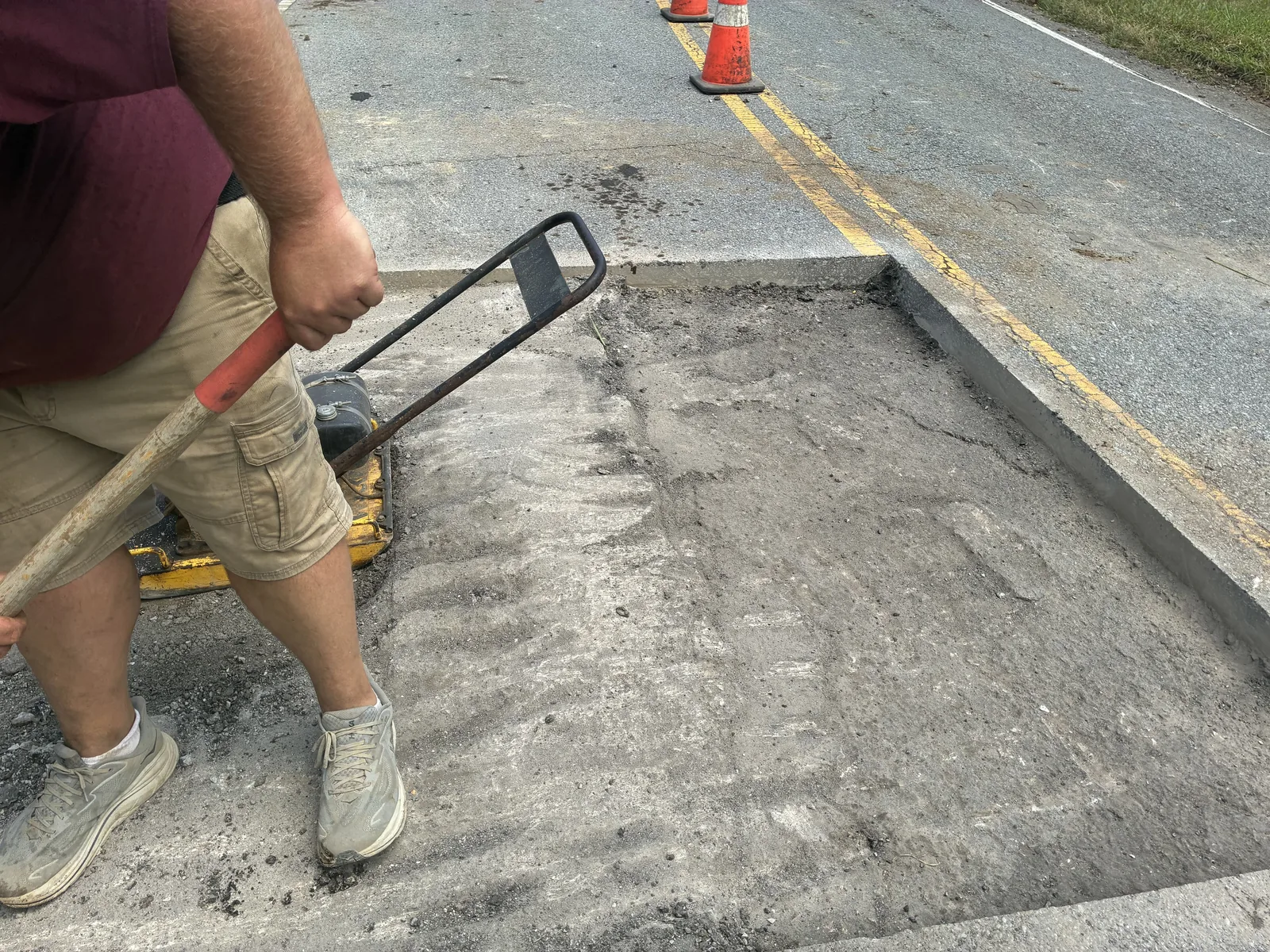 Plate compactor packing the base of a road cut