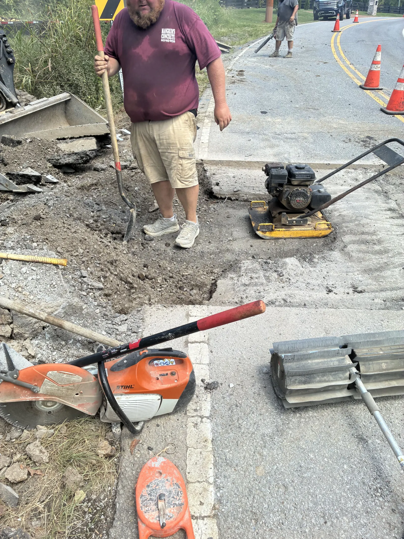 Plate compactor packing the road cut over a sewer crossing